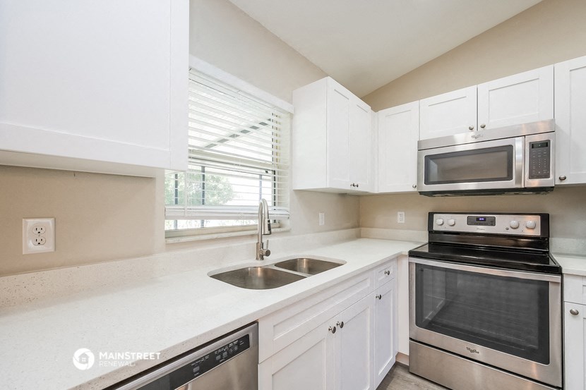 a kitchen with white cabinets and stainless steel appliances and a window