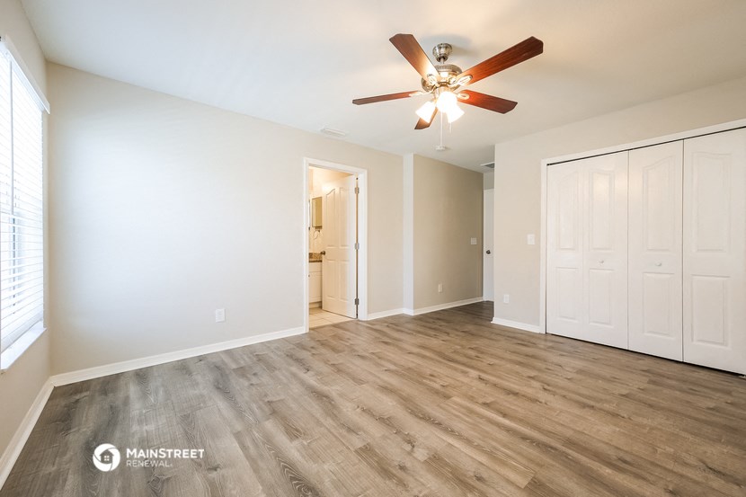 a living room with white walls and a ceiling fan