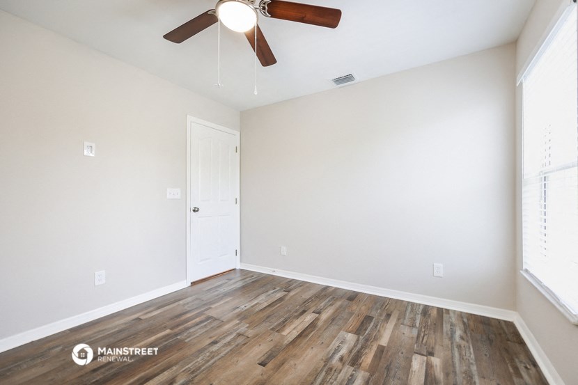an empty room with wood flooring and a ceiling fan