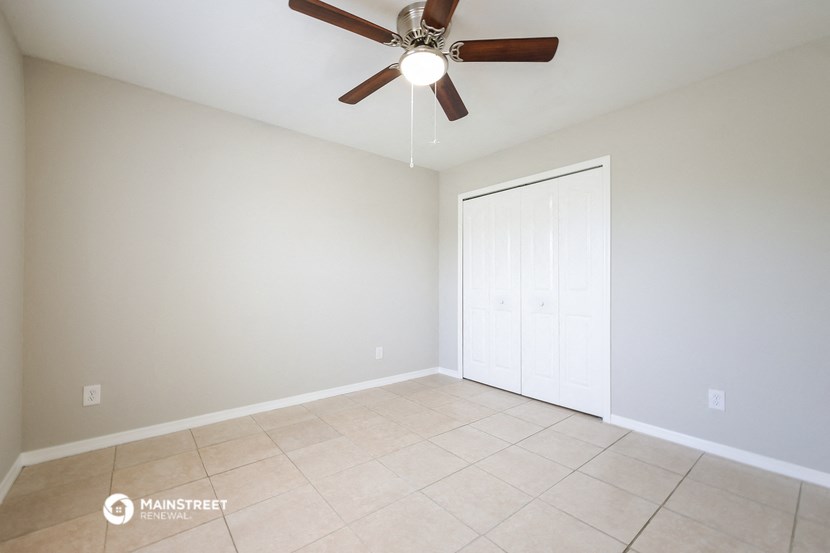 an empty living room with a ceiling fan and a tiled floor
