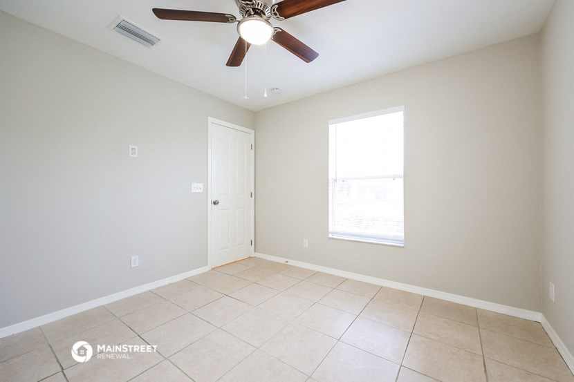 an empty living room with a ceiling fan and a window