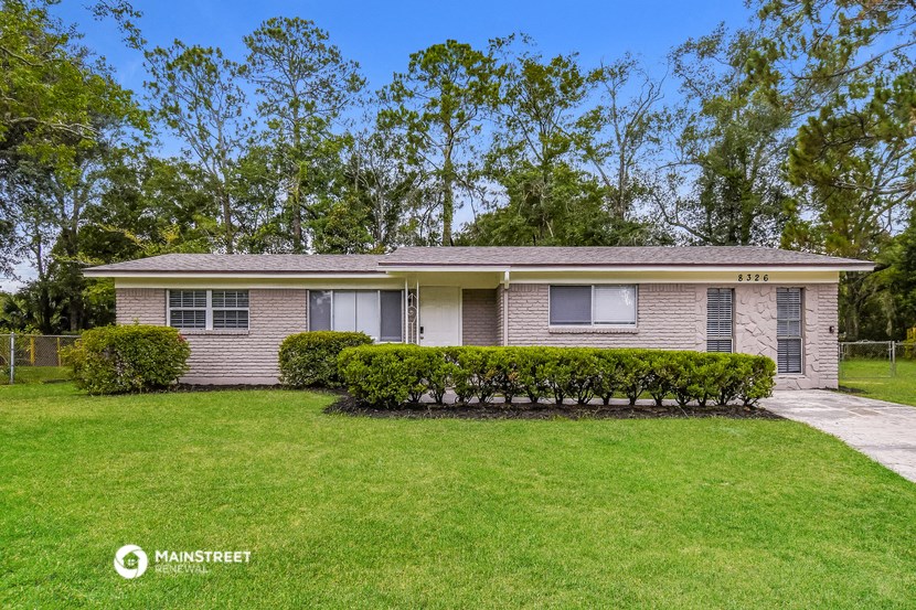 a small brick house with a lawn and trees