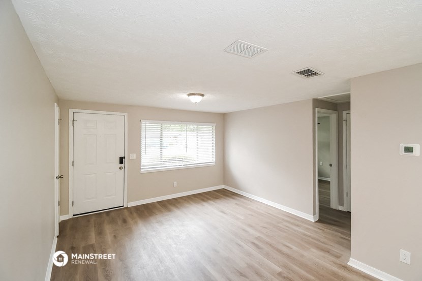 the spacious living room of an apartment with a hardwood floor and white walls