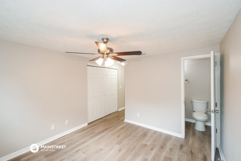 a living room with a ceiling fan and a door to a bathroom