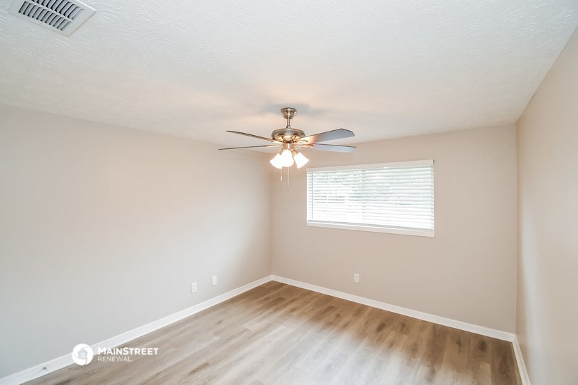 the spacious living room with ceiling fan and wood flooring
