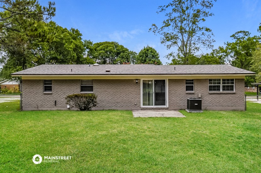 a small brick house with a green lawn and trees