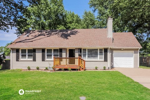 a small tan house with a porch and a lawn