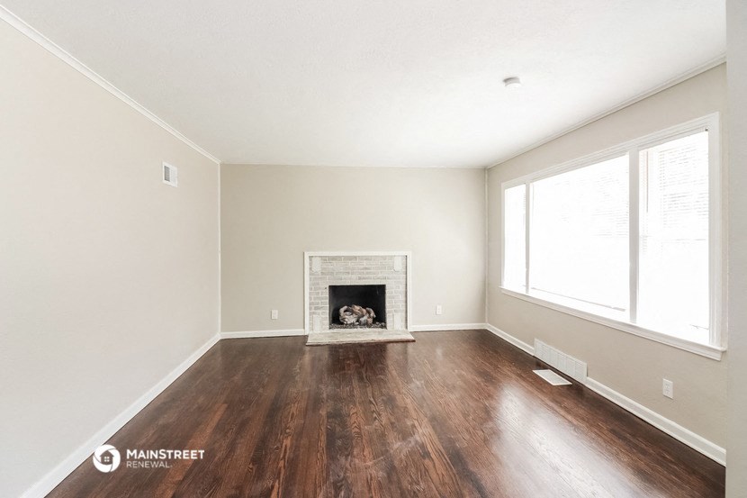 the living room with wood floors and a fireplace
