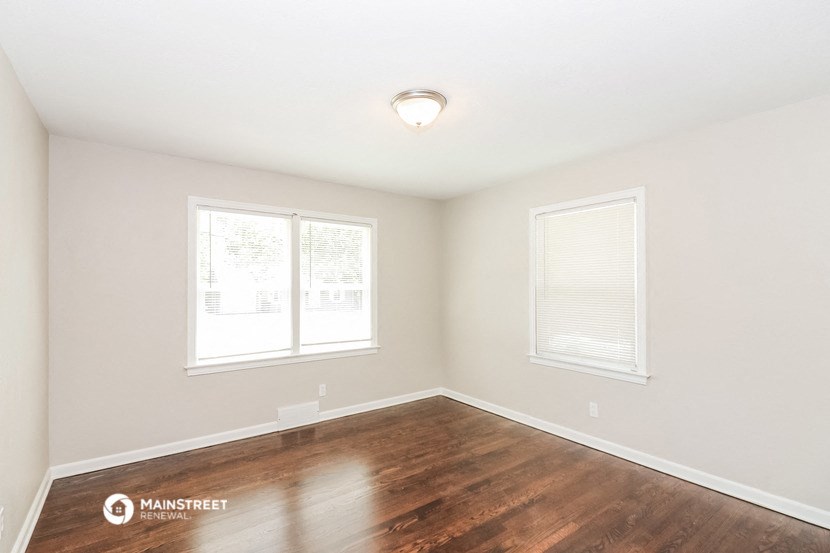 the spacious living room with wood flooring and two windows