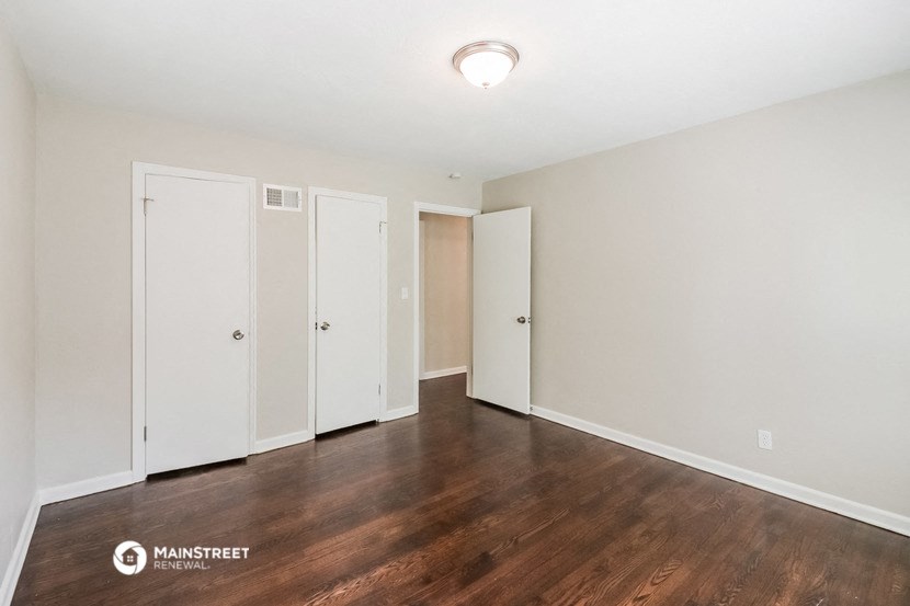 an empty living room with wood flooring and white walls