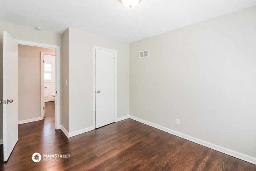 the spacious living room with hard wood flooring and white walls