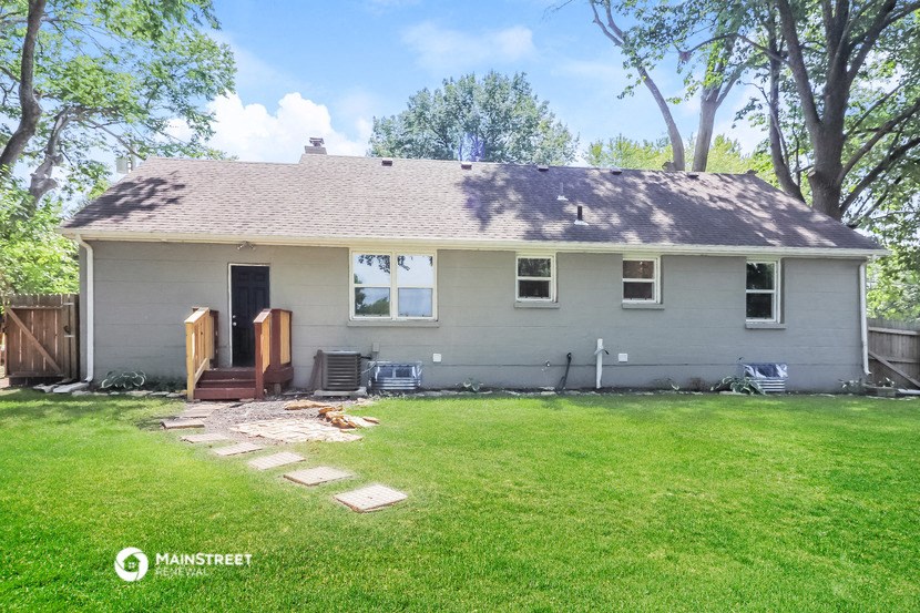 the back of a white house with a yard and grass