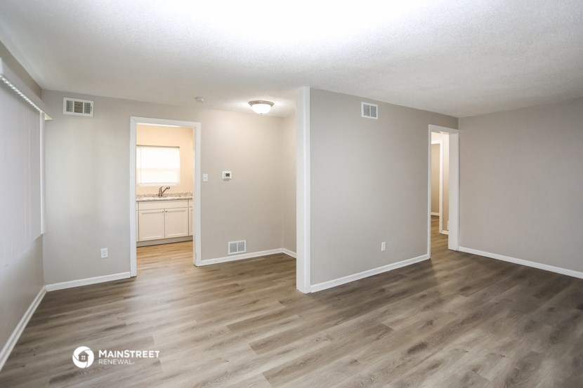 the spacious living room with hardwood flooring and white walls