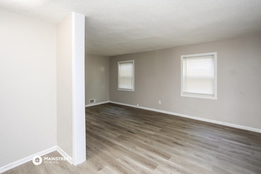 an empty living room with wood floors and white walls