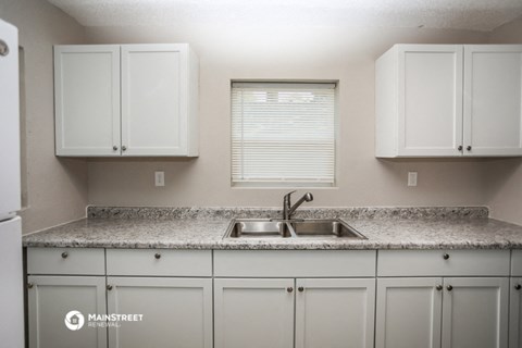 a kitchen with white cabinets and granite counter top and a sink