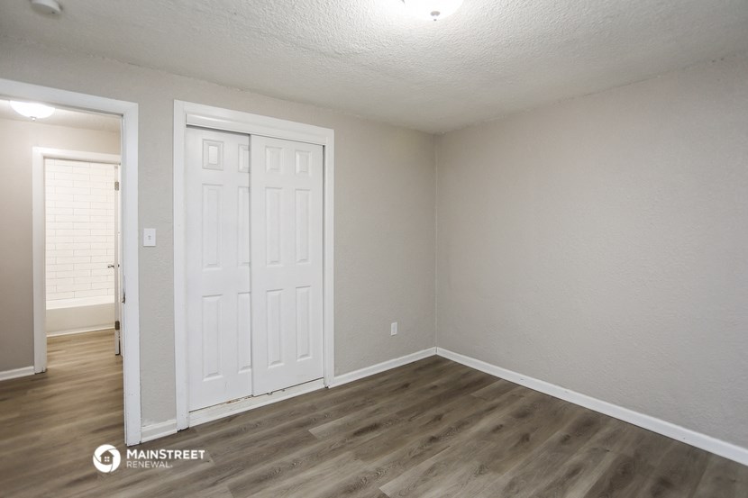 the living room of an apartment with a white door and wood flooring