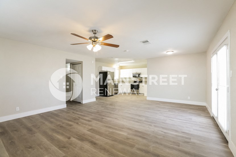 a renovated living room with hardwood floors and a ceiling fan