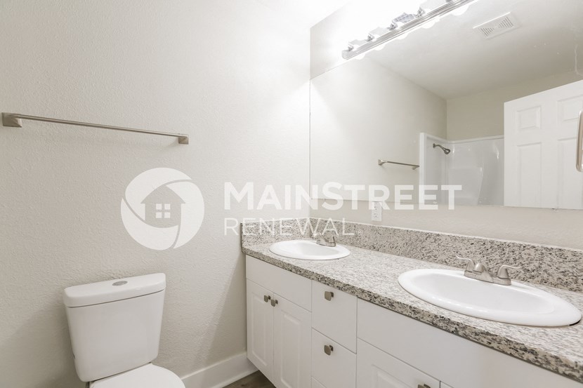 a white bathroom with two white sinks and a toilet