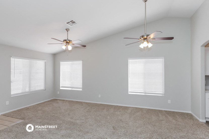 the spacious living room with ceiling fans and windows
