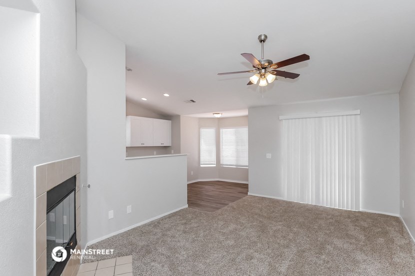 the living room and dining room with fireplace and ceiling fan