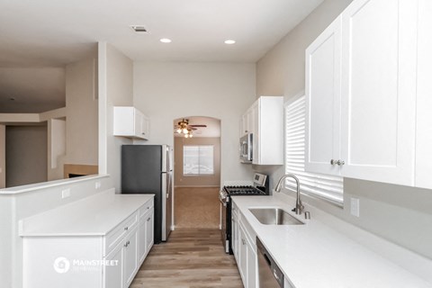 a white kitchen with white cabinets and a black refrigerator