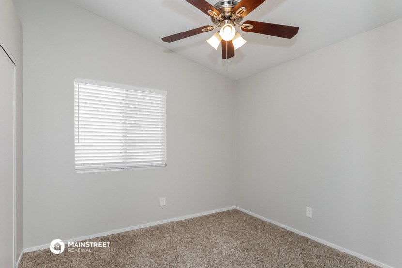 the bedroom has a ceiling fan and a window