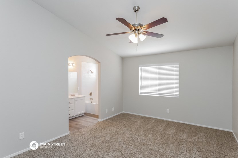 the master bedroom has a ceiling fan and a bathroom