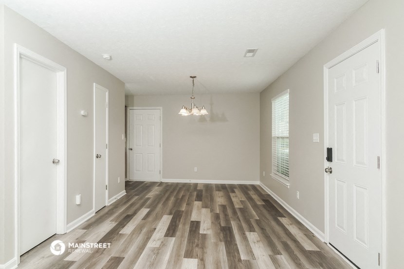 an empty living room with wood floors and white doors