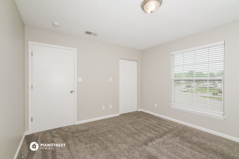 the spacious living room with carpeted flooring and a large window