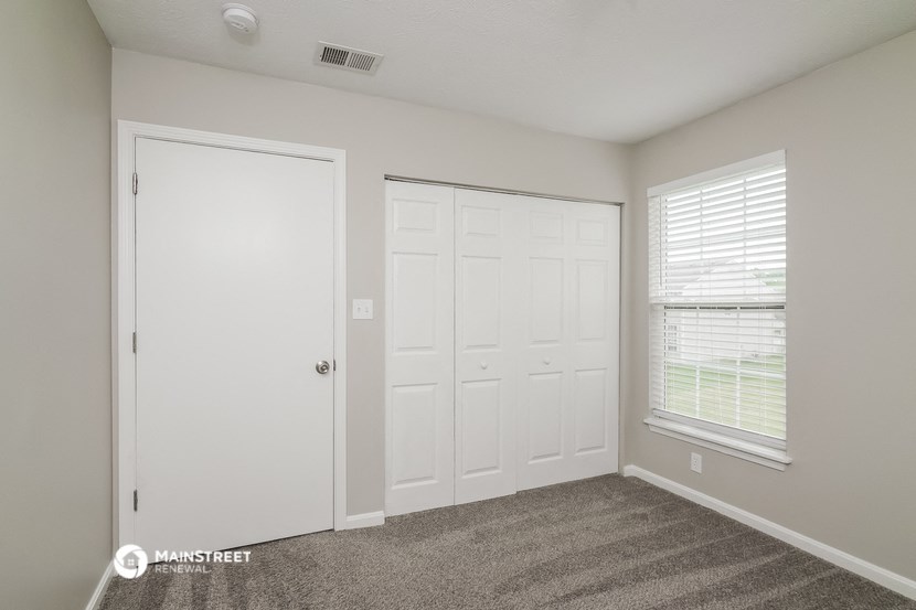 a bedroom with two closets and a door and a window