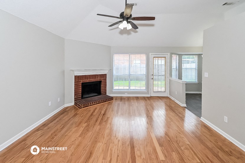 an empty living room with a fireplace and a ceiling fan