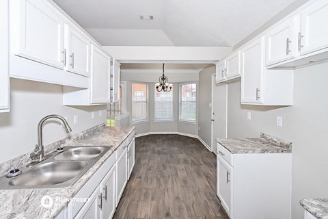 a kitchen with white cabinets and a sink and a counter top