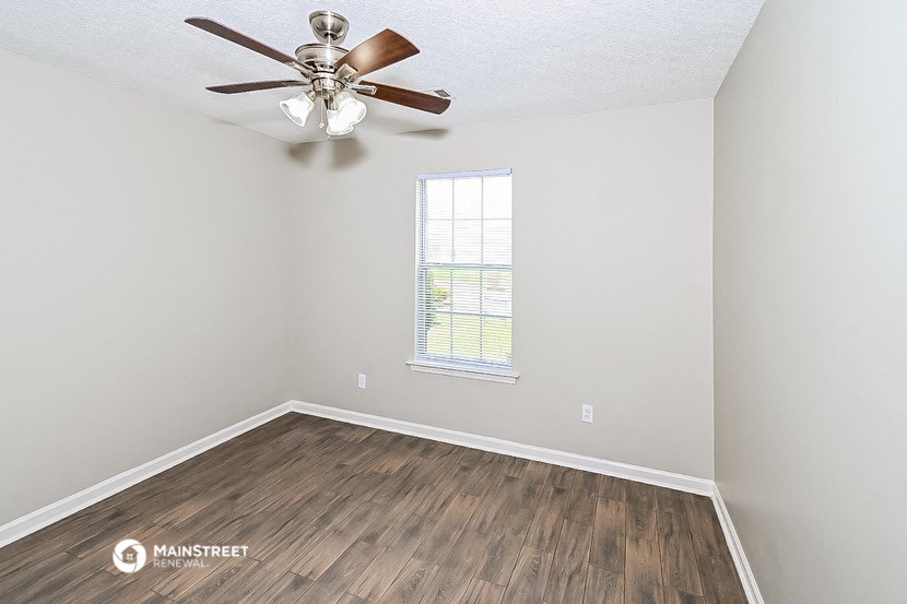 an empty room with a ceiling fan and a window