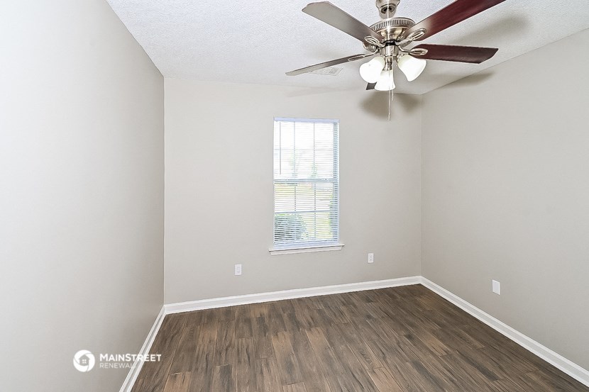 an empty room with a ceiling fan and a window