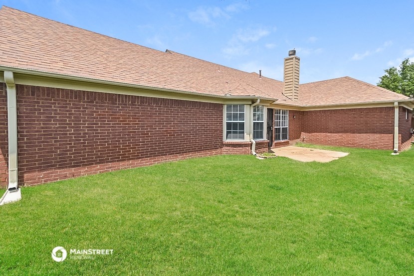 the backyard of a brick house with green grass and a patio