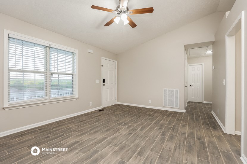 the spacious living room with a ceiling fan and a large window