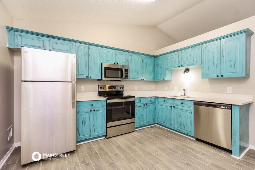 the kitchen is equipped with stainless steel appliances and blue cabinets