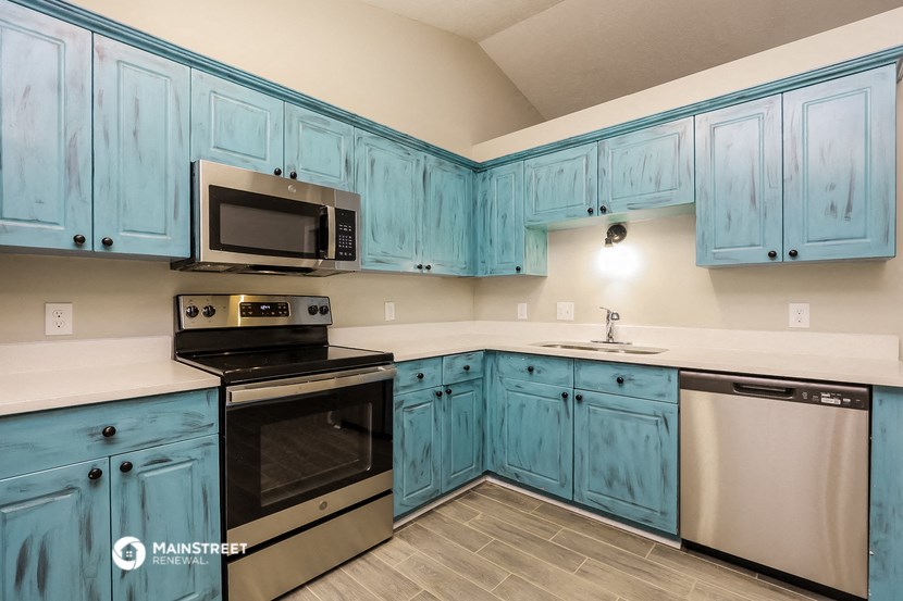 a kitchen with blue cabinets and stainless steel appliances