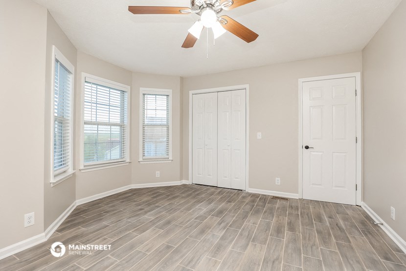 the living room of a new home with a ceiling fan and windows