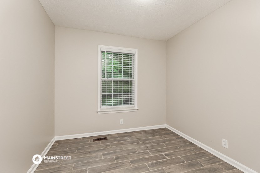 the spacious living room with a large window and wood flooring