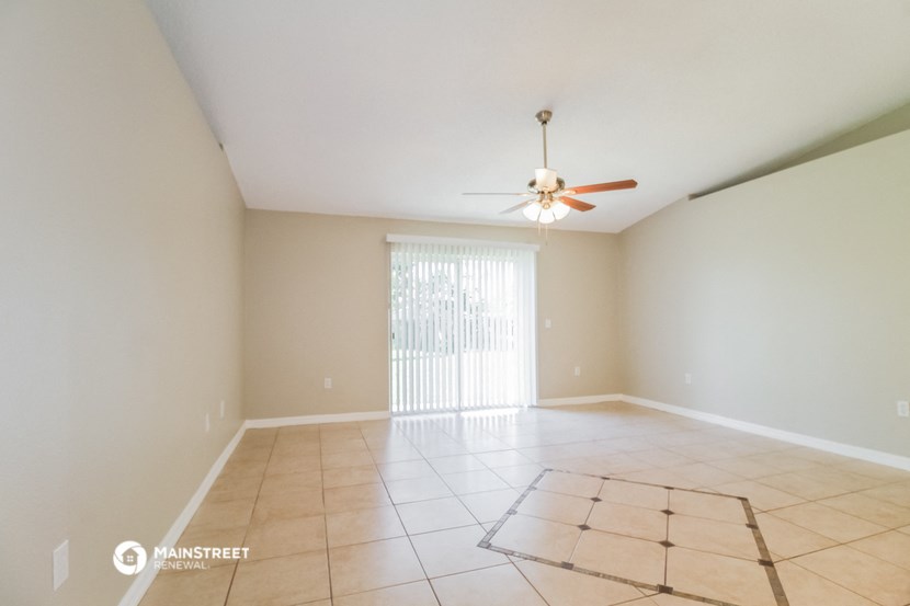 an empty living room with a ceiling fan