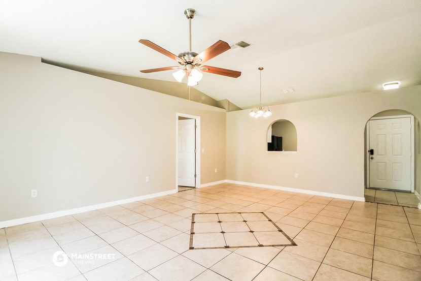 an empty living room with a ceiling fan