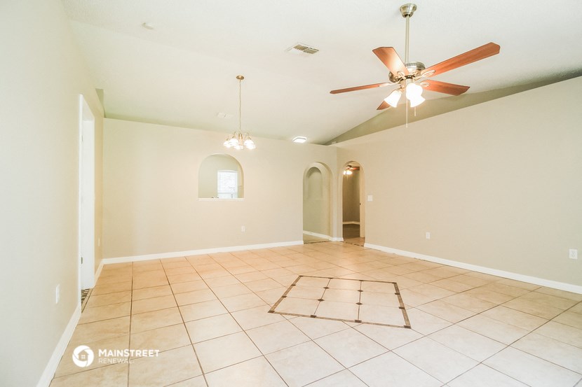 the spacious living room with ceiling fan and tiled floor