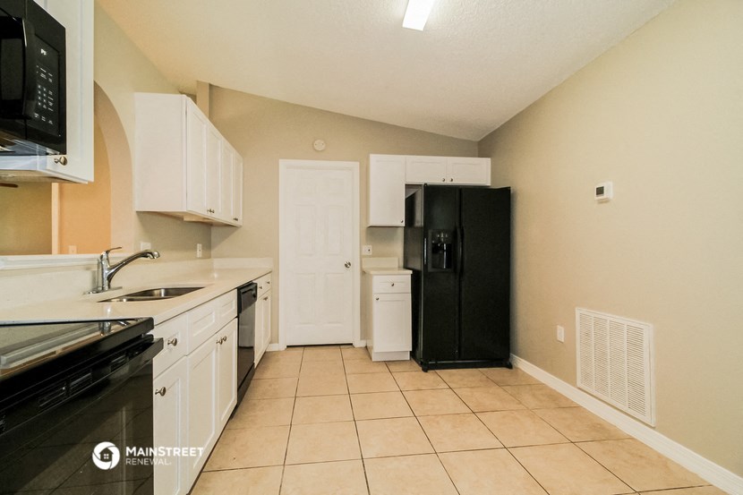 a kitchen with white cabinets and a black refrigerator