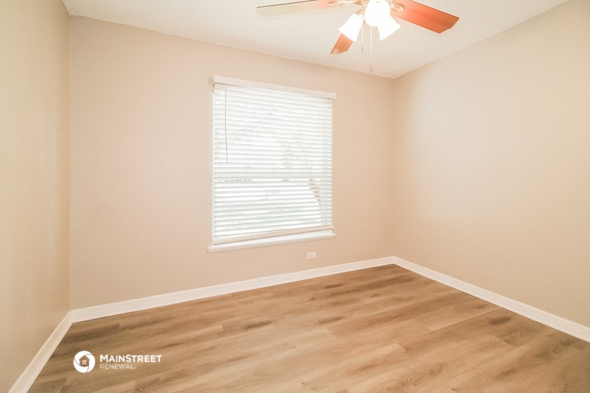 an empty room with a ceiling fan and a window