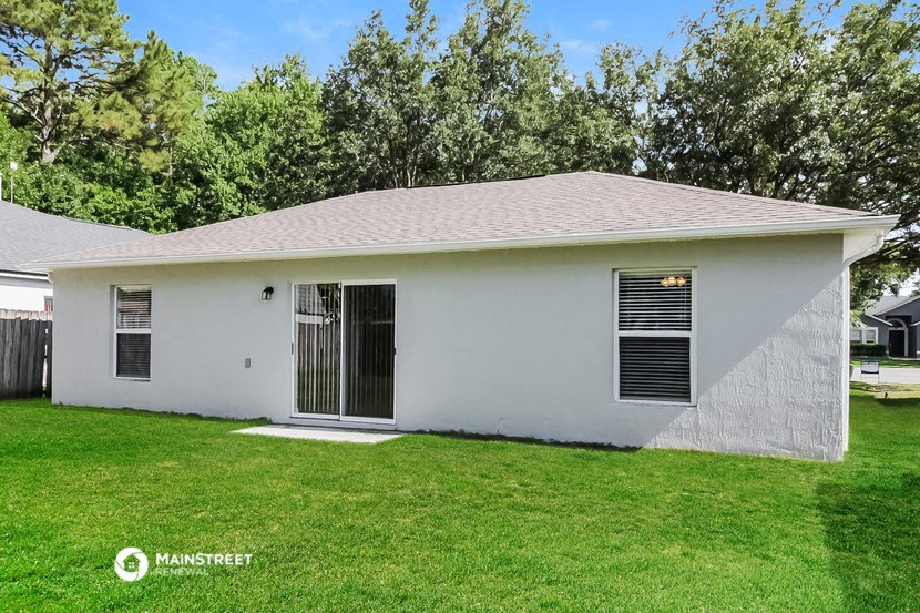 a small white house with a grass yard and trees