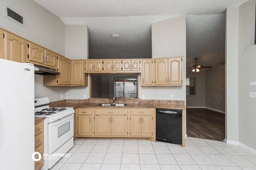 an empty kitchen with wooden cabinets and white appliances