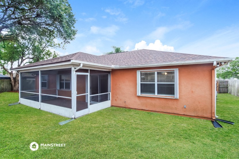 a small brick house with a porch and a lawn