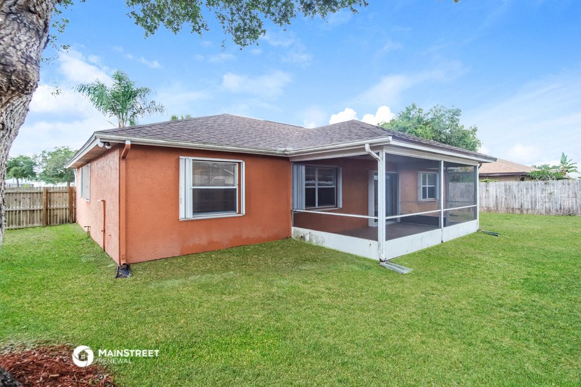 a small brick house with a yard and a fence