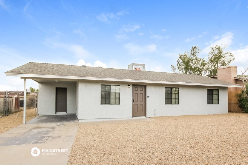 a small white house with a driveway and a roof